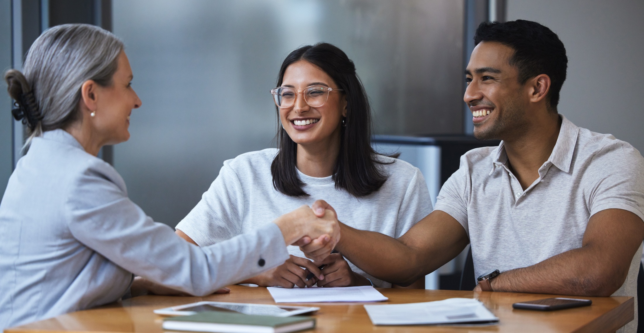 Happy man and woman shaking hands with broker