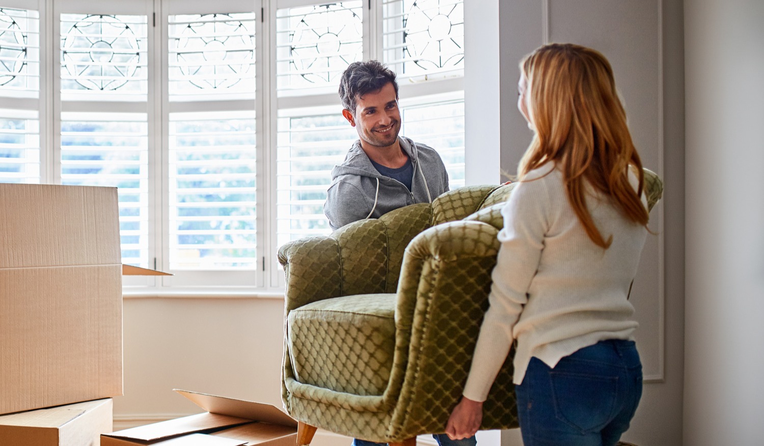 Couple moving an armchair in a new home