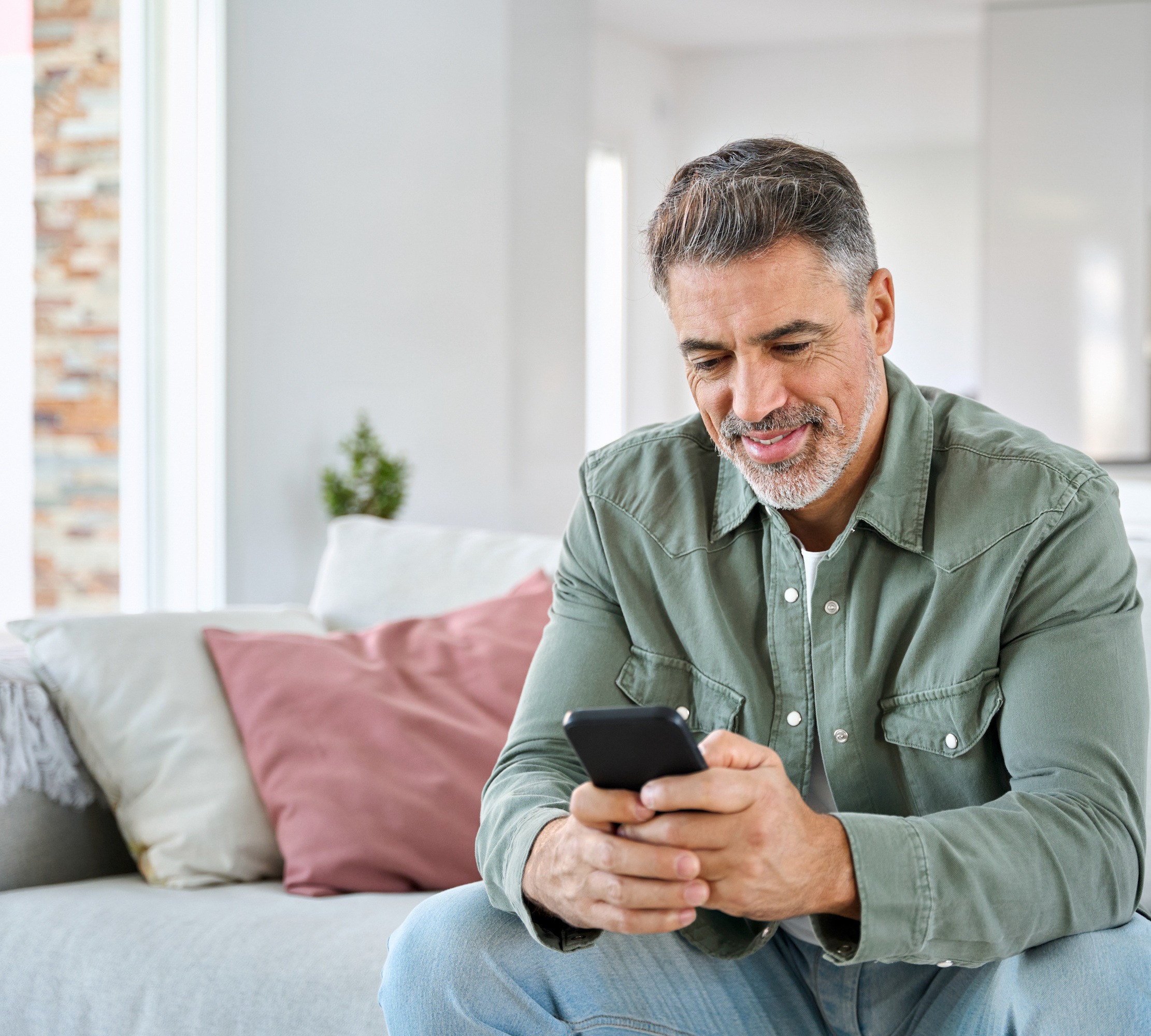 Middle aged man sitting on sofa and using phone