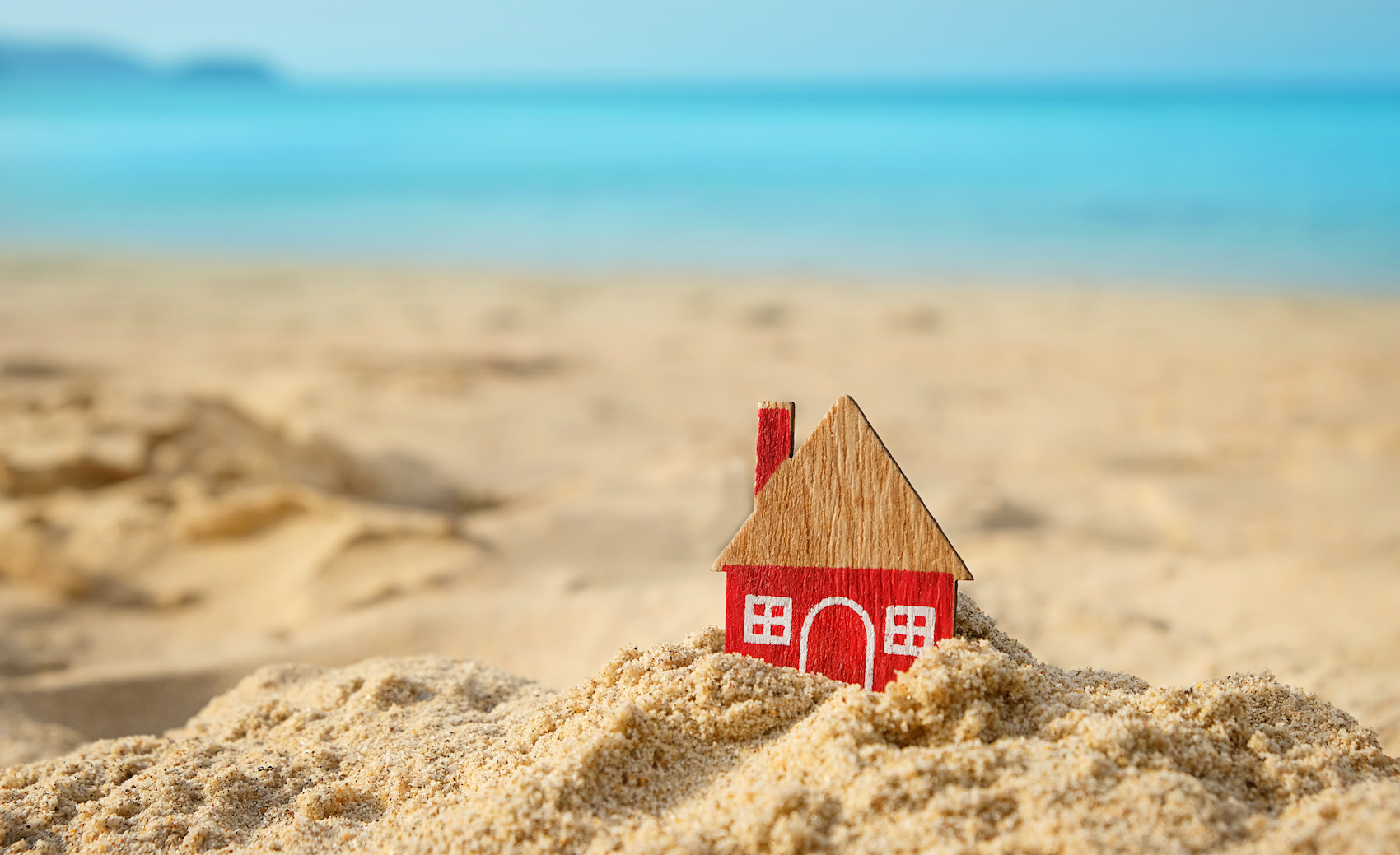 Red miniature house on sand beach