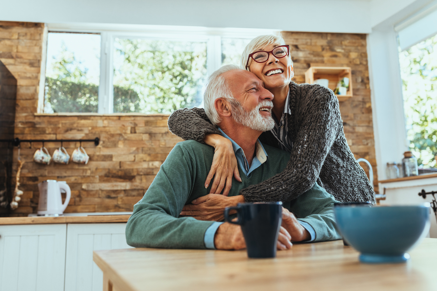 Senior couple sitting in the kitchen and smiling